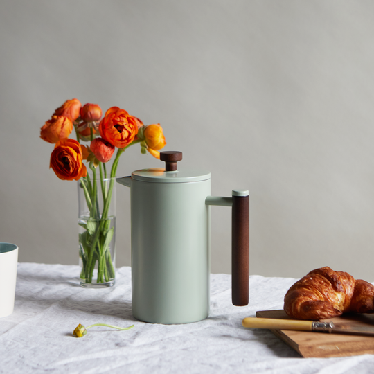 Sage Green French press on table with orange florals in background